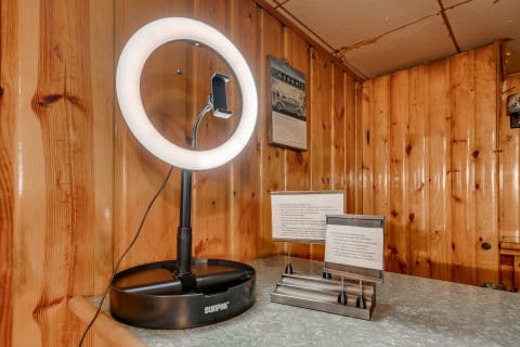 A ring light with a black base and metal instructional stands on a countertop against a wooden wall.