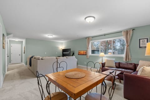 An inviting living room with a sectional sofa, leather couch, dining table, and large window.