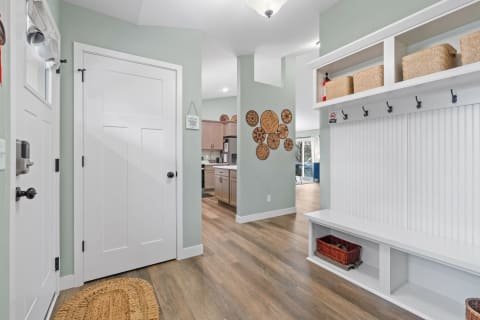 Interior view of a bright entryway, featuring a mudroom and woven baskets