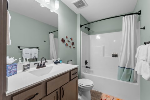 Modern bathroom featuring a light green wall, a stylish vanity, and decorative wall art.