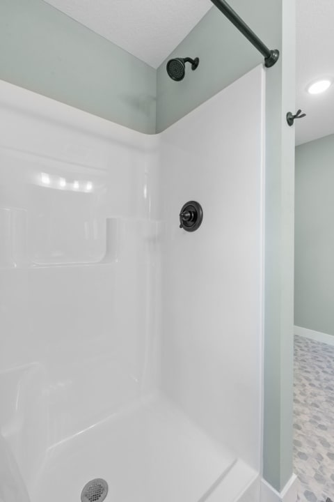 Contemporary shower enclosure with white walls and black fixtures.