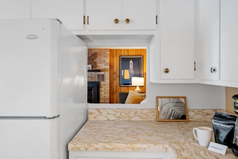 A view from a kitchen into a welcoming living room with wooden walls and a stylish couch.
