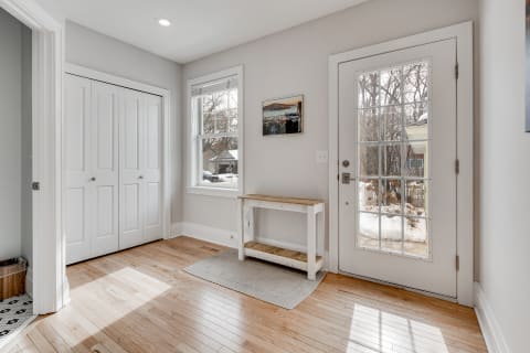 Entryway featuring hardwood floor, white closet doors, a wooden console table, and a large glass-paneled front door.