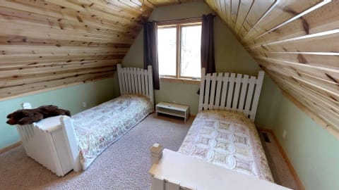 A warm and inviting twin bedroom with wooden ceilings and floral quilts.
