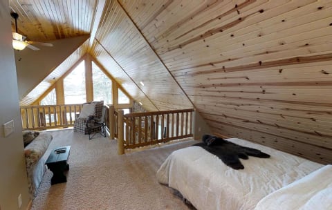 A loft-style bedroom with wooden ceilings, a queen-sized bed, and a cozy seating area.