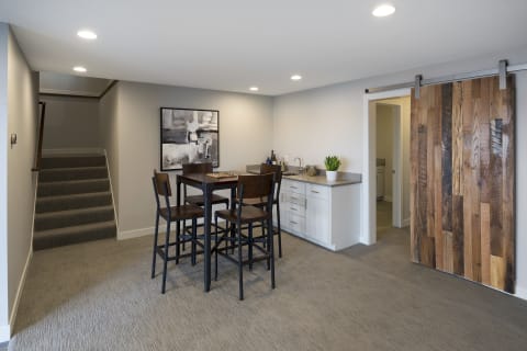 Cozy basement dining area featuring a table, chairs, kitchenette, and a wooden barn door.
