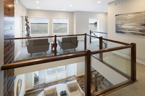 Modern loft overlooking a lake, featuring gray armchairs and wooden accents.