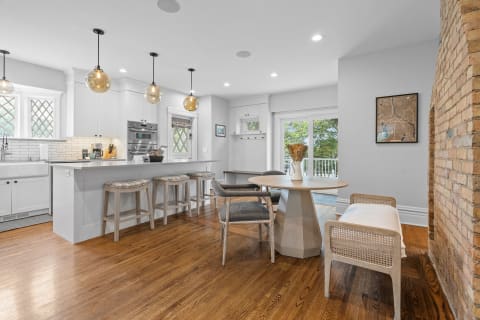 Modern kitchen with white cabinets, glass pendant lights, and a cozy dining area.