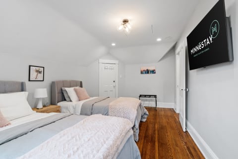 Cozy modern bedroom with two beds, decorative pillows, and a mounted TV.