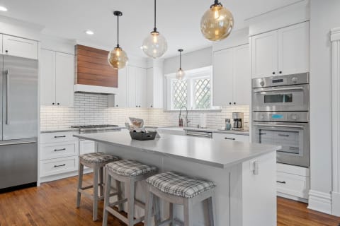 Modern kitchen with white cabinets, gray countertops, and pendant lighting.