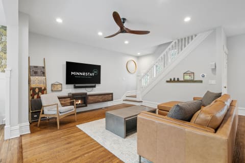 Modern living room featuring a leather sofa, coffee table, and a TV displaying the MINNESTAY logo.