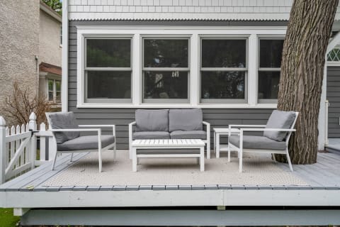 Outdoor seating area with gray cushions and white frames on a deck.