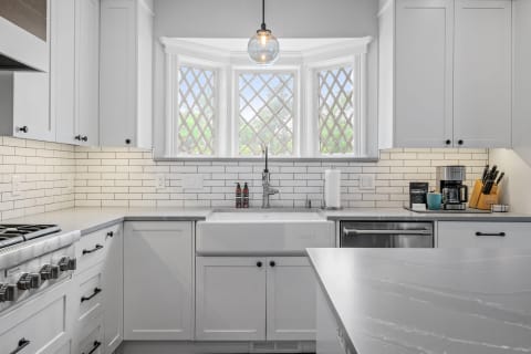 Modern kitchen featuring a farmhouse sink and diamond-patterned bay window.