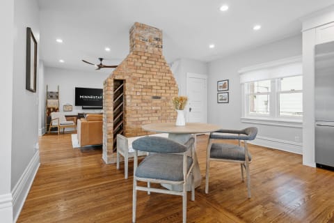 Modern interior with a brick chimney, dining table, and living area.
