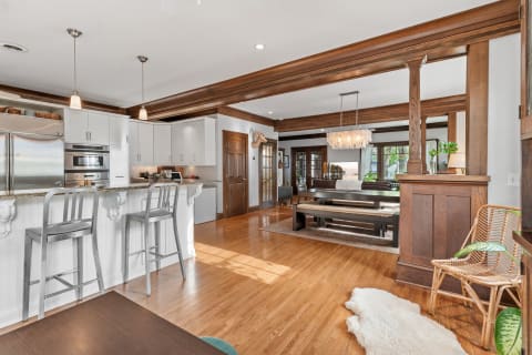 Open-concept kitchen and living room with white cabinetry and wooden accents.