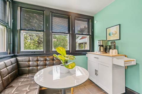 Cozy breakfast nook with a round white table and dark leather seating under mint green walls.