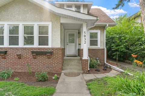 Entrance of a two-tone house with a white door and lush garden.
