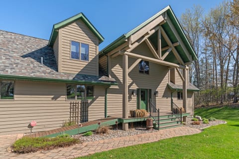 Modern home with wooden siding and green roof in a natural setting.