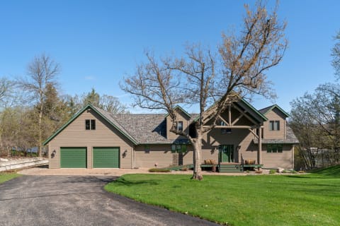 A modern house set against a blue sky with a winding driveway and green grass.