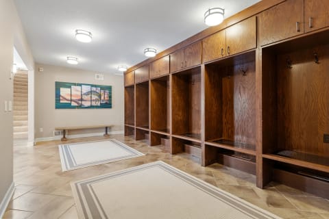 A stylish mudroom featuring wooden lockers, a bench, and modern lighting.