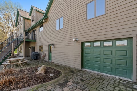 A beige-colored house with a garage, staircase, and outdoor patio area.