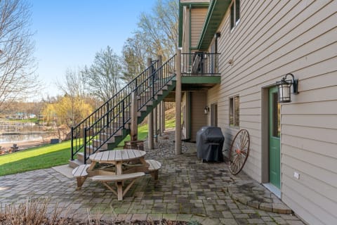 Outdoor space featuring a picnic table, stairs, and a view of water with greenery.