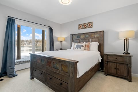 Cozy bedroom with wooden furniture and lake view through sliding doors.