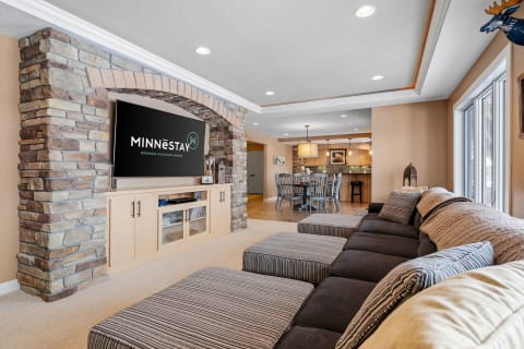 Inviting living room with a sectional sofa, stone wall, and modern television.