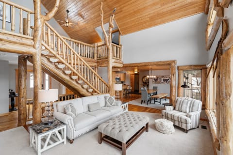 Spacious rustic living area with wooden staircase and comfortable furniture.