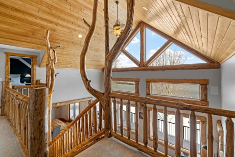 Interior view of a rustic loft with wooden railings and large windows.