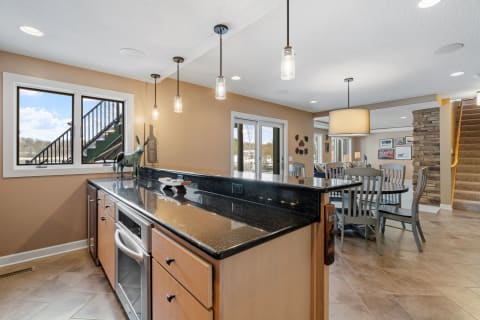 Interior view of a modern kitchen with a granite countertop, decorative wooden piece, and a view of an outdoor staircase.