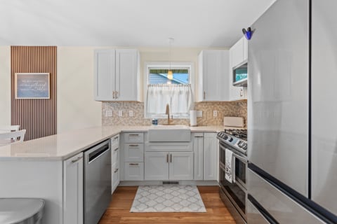 Interior of a stylish kitchen featuring gray cabinets, a farmhouse sink, and contemporary appliances.
