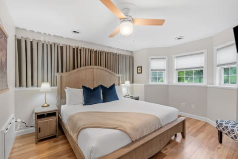 A cozy bedroom featuring a large bed, stylish ceiling fan, and modern decor.