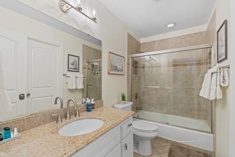 A contemporary bathroom featuring a granite countertop, glass shower, and stylish decor.