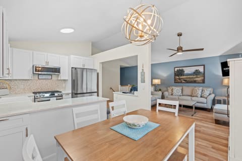 Contemporary kitchen and living room with white cabinets, stainless steel appliances, and cozy seating area.