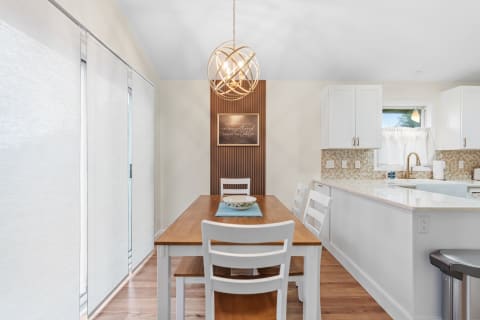 Modern dining area featuring a wooden table, white chairs, and elegant lighting.