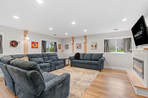 Modern living room with dark blue couches, artwork, and an electric fireplace.