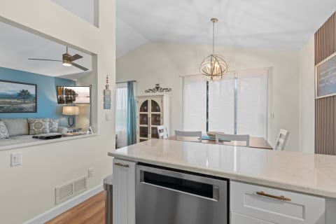 An open-concept kitchen and living room with a light gray sofa, blue accent wall, and modern decor.