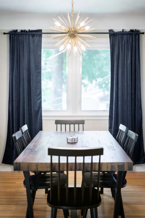 Modern dining room featuring a wooden table, black chairs, and a starburst chandelier.
