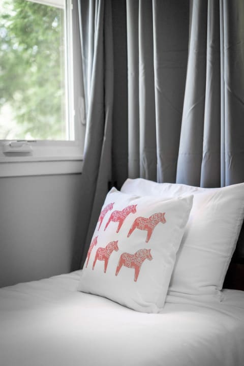 A cozy bedroom with a bed featuring a decorative elephant-patterned pillow and gray curtains.
