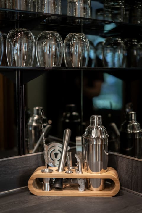 Stylish bar setup featuring cocktail tools on a wooden stand with glassware in the background.
