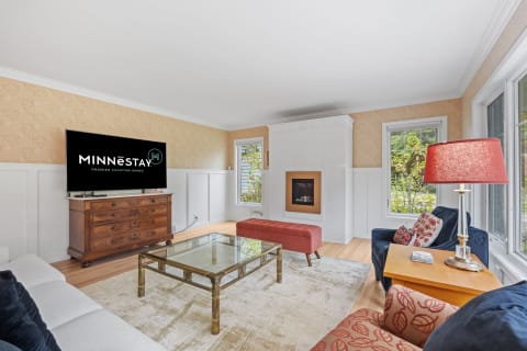 Bright and cozy living room featuring a modern TV, fireplace, and stylish furniture.