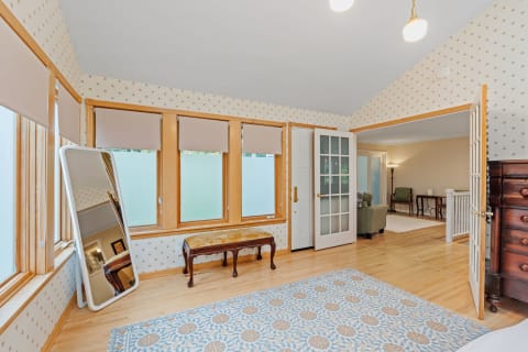 A cozy room with a vintage bench, a large mirror, and decorative wallpaper.