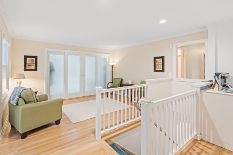 Cozy living area featuring green furniture, frosted glass doors, and wooden flooring.