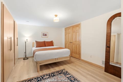 Cozy bedroom with a bed, decorative accent pillows, a lamp, and wood accents.