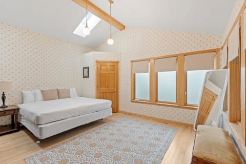Cozy bedroom featuring a made bed, wooden decor, and natural light.