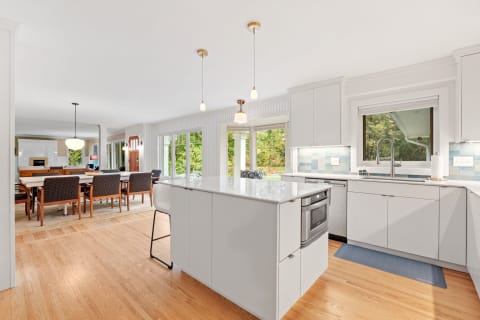 Modern kitchen with white cabinets, a large island, and an adjoining dining area with large windows.