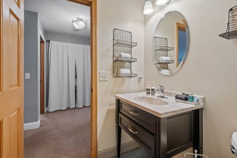 A stylish bathroom with a black vanity, light countertop, and neatly arranged towels on shelves.
