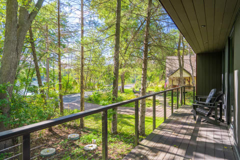 View from a balcony surrounded by tall trees and a path leading to a house.