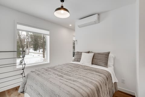 Cozy modern bedroom with a bed dressed in gray and winter scenery outside the window.
